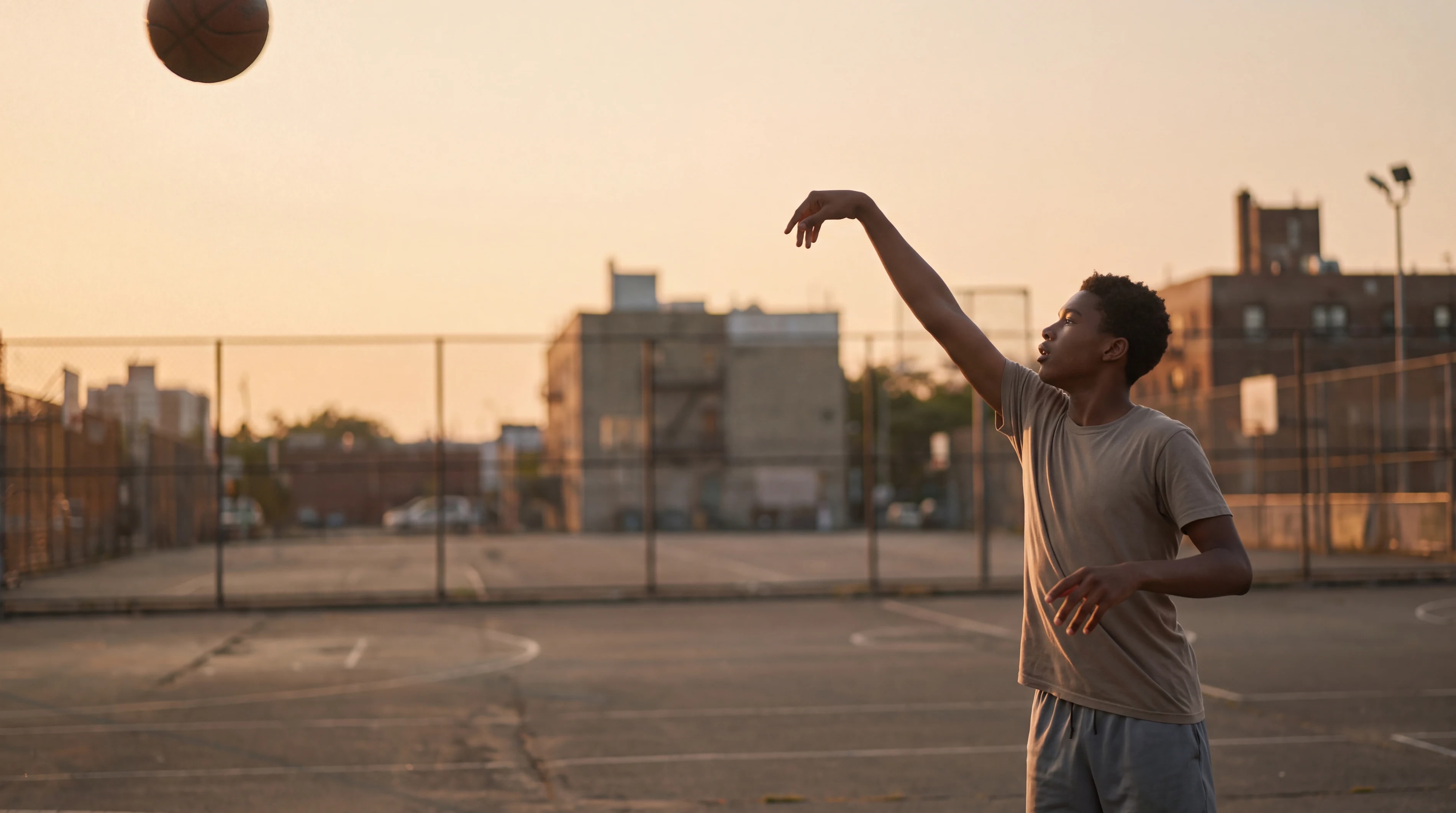 Un jugador termina un tiro a canasta al atardecer.